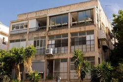Typical Tel Avivian building in Old North district. Big open windows old facade with palms around. Tel aviv, Israel