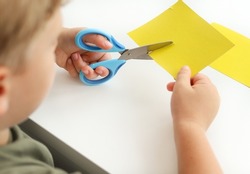 A child cuts colored paper with scissors.