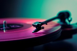 Vinyl DJ turntable in club lighting. close-up. pink tint