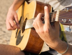 young man playing an acoustic guitar on the beach
