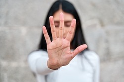 woman raises her hand to say enough is enough. Campaign to stop violence against women. Latina woman with her hand covering her face