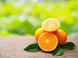 Pile orange fruit and orange slice with green leaf on wooden table of natural background with copy space