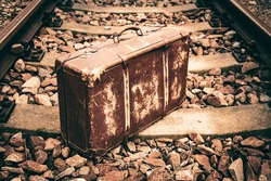 Old worn suitcase on the rails