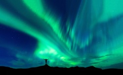 Aurora borealis with silhouette standing man on the mountain.Freedom traveller journey concept