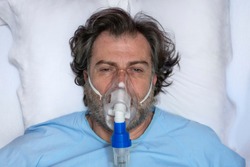 Aerial portrait of an elderly person, with oxygen mask, in a hospital bed