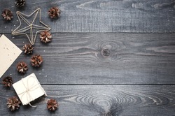 Gift, card, pine cones, metal star on the dark wooden textured table