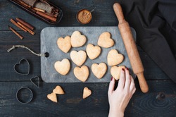 Female hand holding the baked cookies-hearts on the vintage wooden table