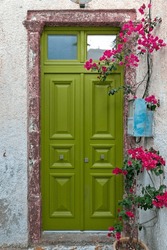 Beautiful green, wooden door with bougainvillea of an old mansion at the village of Pyrgos Kallistis, in Santorini island, Cyclades, Greece