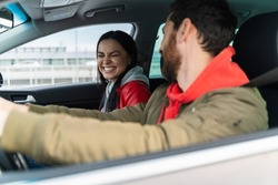 Brunette caucasian woman laughing out loud while having conversation with her husband during the road by car. Journeys concept