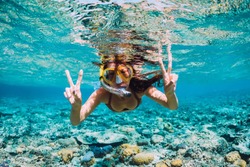 Happy young woman swimming underwater in the tropical ocean