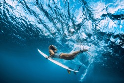 Surfer woman with surfboard dive underwater with ocean wave.