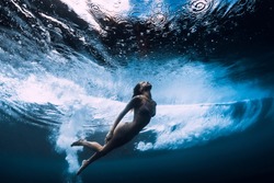 Woman in bikini dive without surfboard underwater with ocean wave. Duck dive under barrel wave