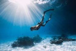 Woman freediver glides with fins. over sandy sea. Freediving and beautiful sunlight in blue ocean