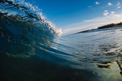 Perfect glassy wave in sea. Crashing surfing wave and blue sky
