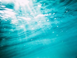Underwater wave in tropical sea and sun rays. Water texture in ocean