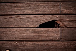Hole in brown wooden wall or floor. Damage, broken wood surface. Horizontal
