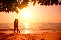 Red toned picture of a couple on a tropical beach at sunset