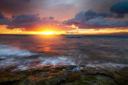 Sunset over rocky coast of Apo island, Philippines
