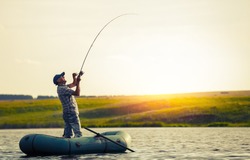 Mature man fishing on the lake from inflatable boat