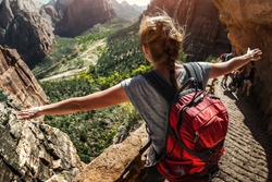Woman hiker standing with raised hands and watching valley view of Zion National Park, USA
