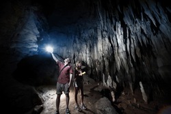 Young couple exploring huge cave with torches