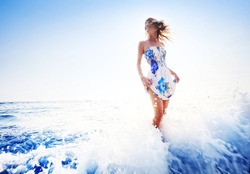 Young smiling woman having fun standing in blue sea water