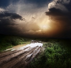 Muddy wet countryside road and dark storm clouds