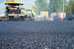 Close up view on the new asphalt road on which special equipment is working. Blurred photo of construction site.