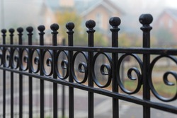 Beautiful metal fence on the background of houses in the fog in the autumn. Guardrail close up.