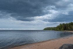 The beach by the lake before a thunderstorm. Dark clouds over a calm sea.