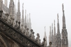  the roof of the Milan's Duomo or cathedral under a heavy day of fog.  the pinnacles, details and sculptures of this magnificent building located in Italy. 