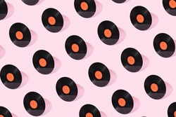 Black old vinyl record with orange clean label isolated on pastel pink background. Creative retro pattern music concept. Gramophone sound. DJ turntable. Front view.