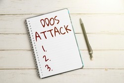 Writing displaying text Ddos Attack. Concept meaning disturbed access to the normal server caused by malicious system Keyboard Over A Table Beside A Notebook And Pens With Sticky Notes