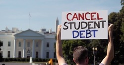 A man holds an CANCEL STUDENT DEBT protest sign in front of the White House on a sunny summer day. Student debt was a hot topic during the COVID-19 pandemic.	