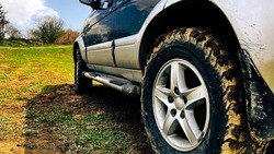 Muddy wheel of off-road vehicle. All-terrain vehicle parked on dirt terrain.