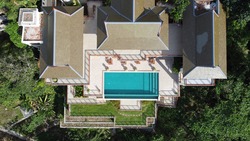 Aerial drone view to villa with swimming pool on the rocky coast in Thailand. Top view of villa and pool on the cliff.
