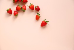 Scattered fresh strawberries on a pink background. Free space.