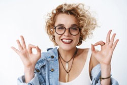 That deal, okay I agree. Portrait of satisfied positive and charismatic happy young female showing ok signs and smiling in approval, recommend awesome salon as liking new haircut over white background