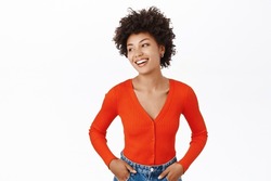 Portrait of smiling, beautiful african american woman with afro curly hair, wearing red blouse, standing over white background