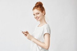Beautiful ginger girl smiling holding phone looking at camera.