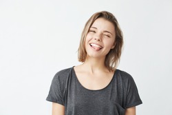 Funny cute young girl smiling winking showing tongue looking at camera over white background.