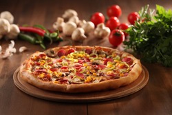 whole italian pizza on wood table with ingredients 