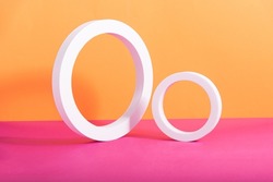 Abstract geometric composition made of two white circular frames on orange and pink background. Wallpaper. Rectangular with copy space. Isometric layout. Minimal concept