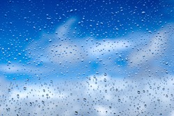 Rain drops on the glass. Beautiful blue and white sky. Sky background