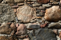 Background texture of an ancient stone wall on a medieval fortress with irregular pattern of rough stone . High quality photo