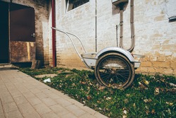 Wheelbarrow on a grass field with an interesting background of an old house . High quality photo