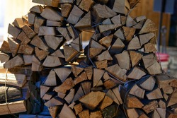 A beautiful closeup view of cut and split firewood stacked outdoor up against a shed under roof . High quality photo