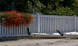 white kayaks on the background of a white wooden fence, pots with flowers on the fence . High quality photo