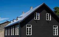 black wooden house under a gray roof against a blue sky. building architecture. High quality photo
