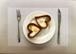 14 Valentine's Day Breakfast. Fried egg inside heart shaped sausage in a white plate. Fried chicken eggs for breakfast. A delicious dish of eggs with yolk and protein. High quality photo